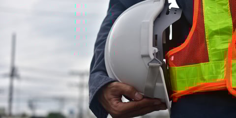person holding hard hat wearing safety vest