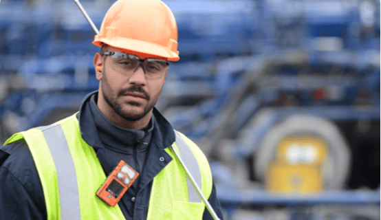 man wearing personal protective equipment and a personal gas detector with LEL sensor on his collar looks forward