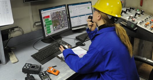 in a safety control room, a safety manager sits in front of a dashboard displaying a gas exposure alarm. They call for help