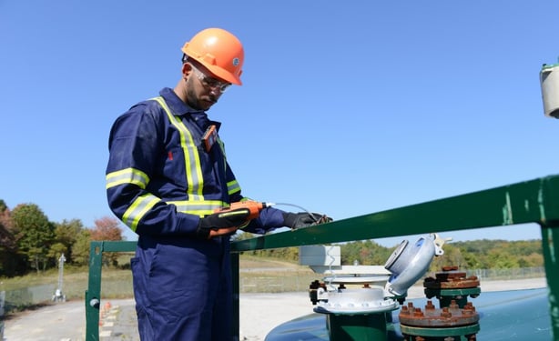 industrial worker uses a gas monitor with a sampling pump to take a gas reading within a tank