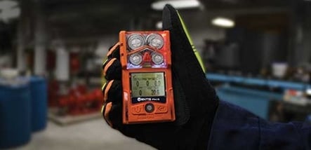 gloved hand holding a personal gas detector