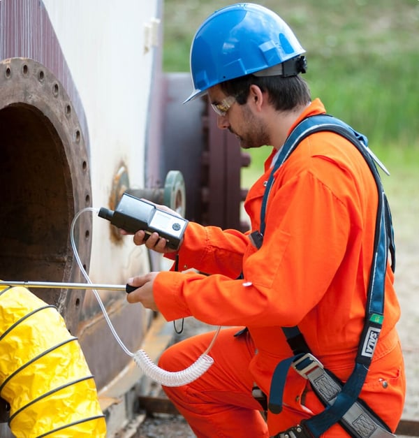 picture of a man in an orange jacket using an Industrial Scientific confined space monitor
