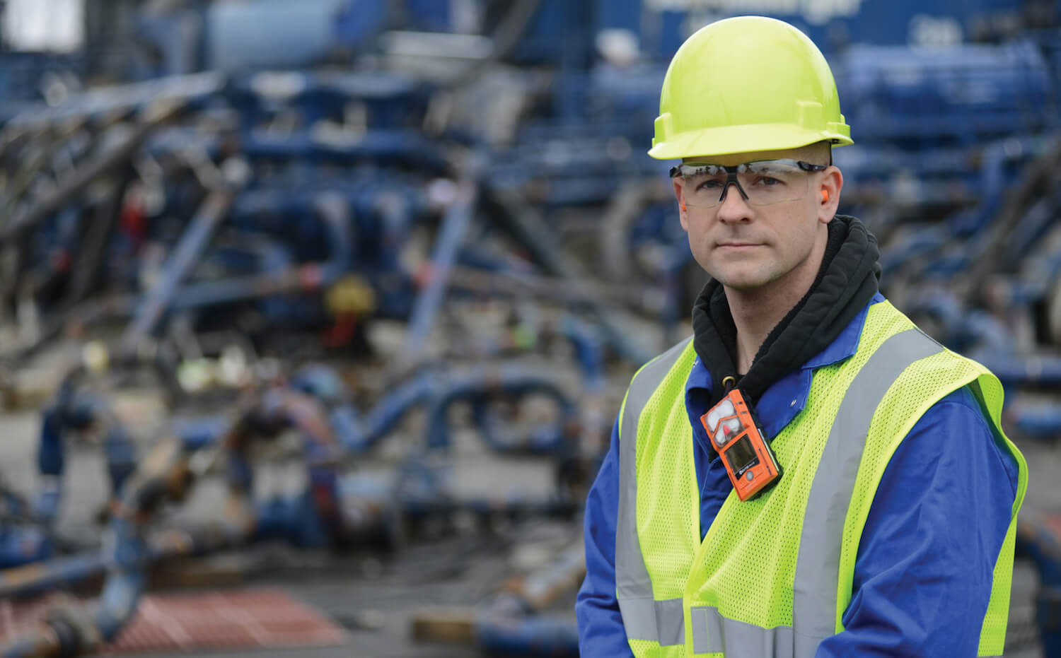 A worker wears a personal gas monitor on the collar of his shirt, or the breathing zone