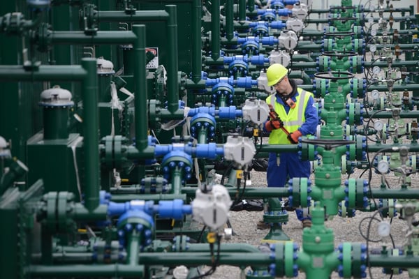 a lone worker monitoring hazardous gases works in a row of pipes