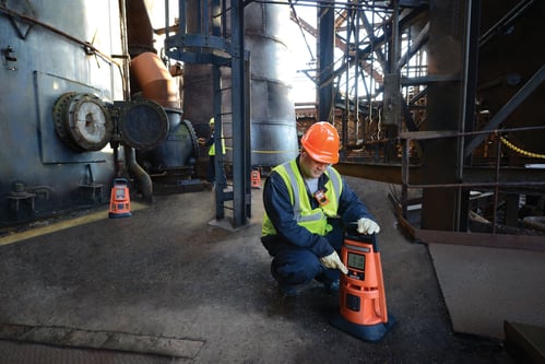 worker kneeling to turn on an area gas monitor