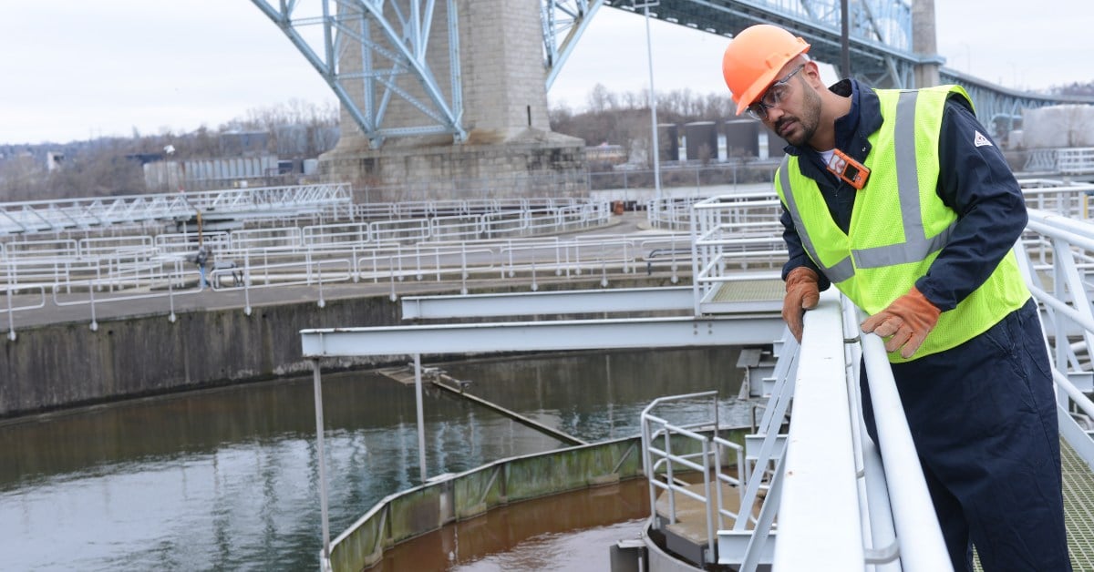 A worker stands on a bridge at a water treatment plant